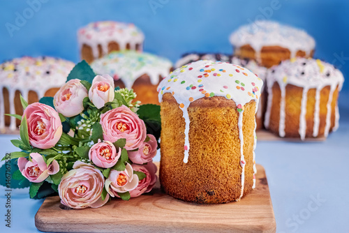 holiday card with image of freshly baked paska and flower bouquet on wooden board on blue background, close-up