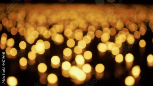 Abstract view of many blurry golden lights scattered across a dark surface creating a bokeh effect