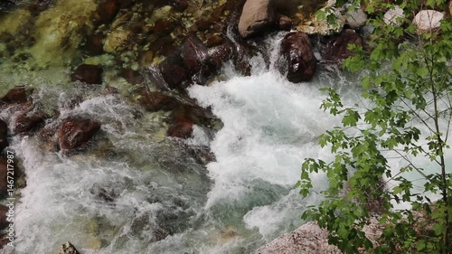 Top down view of a mountain stream featuring clear fresh water as it flows and meanders through and around various rocks and stones in its natural course