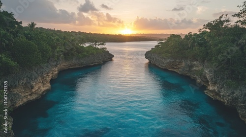 Tranquil, turquoise waterway at sunset, carved by nature. Lush greenery surrounds a calm body of water, narrowing into a channel. Sunlight bathes the scene in warm hues