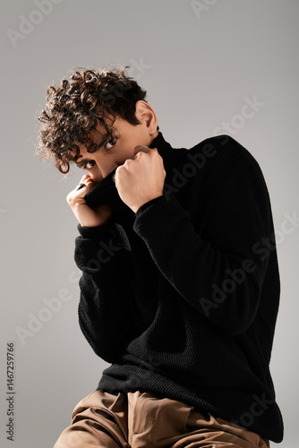 Stylish young man poses confidently with a trendy black sweater in a modern setting