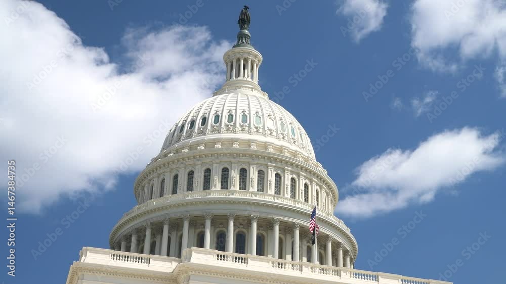 Capitol dome against the blue sky in Washington, D.C. and the U.S. flag in the wind
