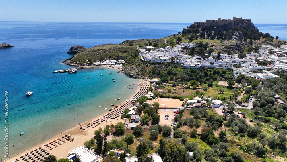 Aerial drone photo of stunning traditional village and medieval archaeological site of Acropolis of Lindos overlooking main beach and Saint Paul's bay, Rhodos island, Dodecanese, Greece