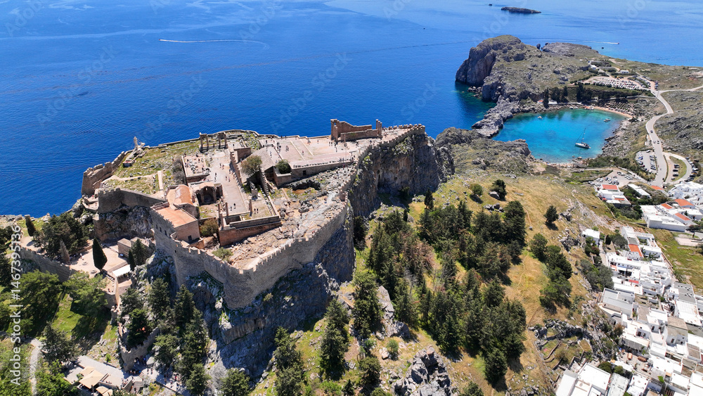 Aerial drone photo of stunning traditional village and medieval archaeological site of Acropolis of Lindos overlooking main beach and Saint Paul's bay, Rhodos island, Dodecanese, Greece