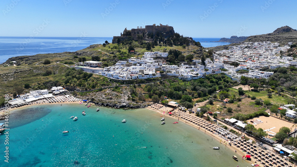 Aerial drone photo of stunning traditional village and medieval archaeological site of Acropolis of Lindos overlooking main beach and Saint Paul's bay, Rhodos island, Dodecanese, Greece