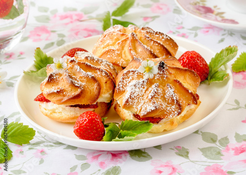 Cream puffs cakes or profiterole filled with whipped cream and strawberries