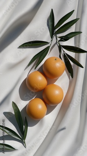 Three fresh oranges arranged with green leaves create a striking composition against a calming blue backdrop