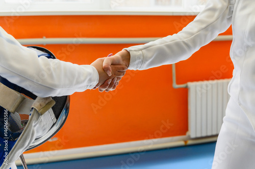 Canvas-taulu Close-up of female fencers shaking hands after match indoors.