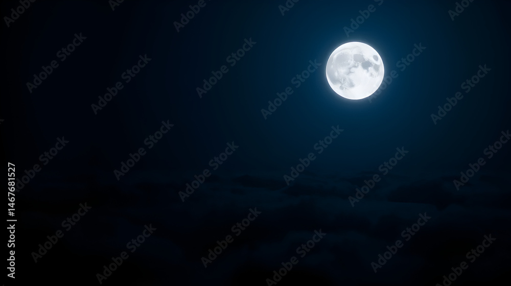Fototapeta premium Full moon shining bright above dark clouds in the night sky with a deep blue color cast