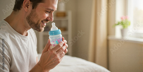 Father holding baby bottle smiling in a bright room  