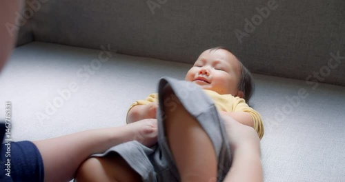 Adorable Asian toddler smiles brightly while holding hands with mother, capturing a joyful and tender bonding moment. cheerful expression and warm indoor convey happiness love and family connection.