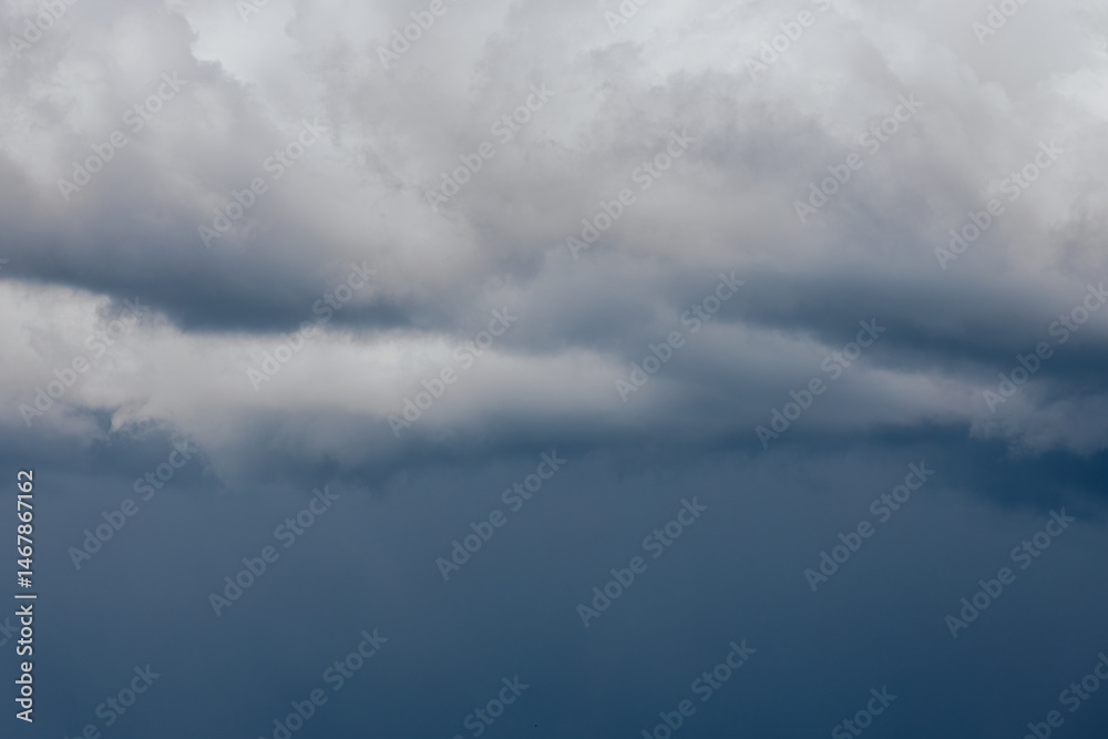 Obraz premium Thick storm clouds stretch across the sky with a visible curtain of rain falling below, creating a dramatic and moody atmosphere ample copy space.