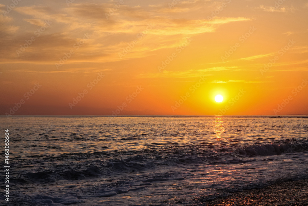 Fototapeta beautiful and colorful sunset, warm light and many clouds, sea waves on the sea coast