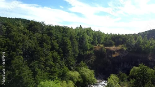 Vista aérea del río Coyhaique rodeado de árboles y montañas verdes en la inmensidad patagónica.