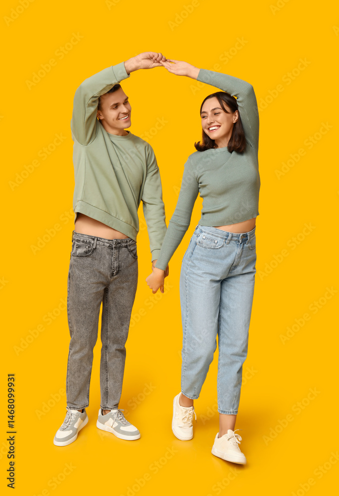 Obraz premium Happy young couple dancing together on yellow background