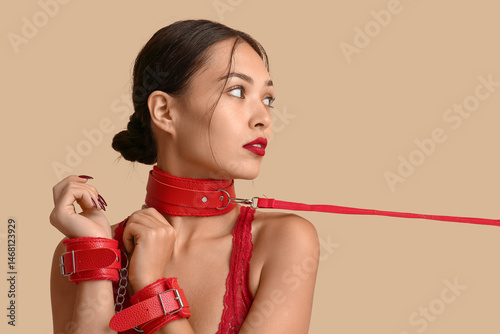 Sexy young woman in red handcuffs and collar on color background. Erotic concept