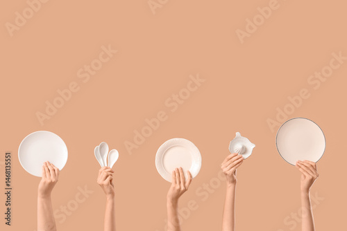 Female hands with plates, ceramic scoops and citrus squeezer on beige background