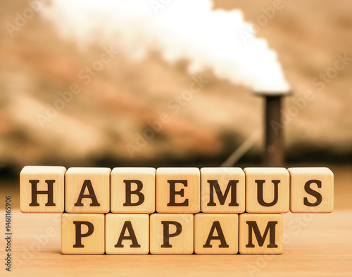 Habemus Papam written on wooden cubes with industrial smokestack in the background photo