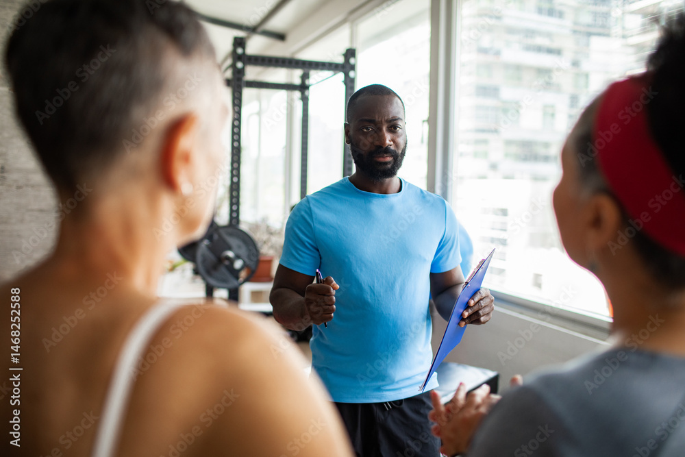 Mature women working out at gym with personal trainer guiding Mature women working out at gym with personal trainer guiding