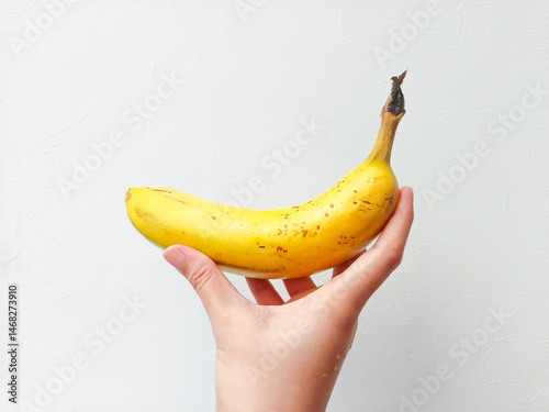 Fresh ripe banana held in hand on clean white background—perfect for nutrition, healthy living, diet, food blogs, or tropical fruit marketing visuals