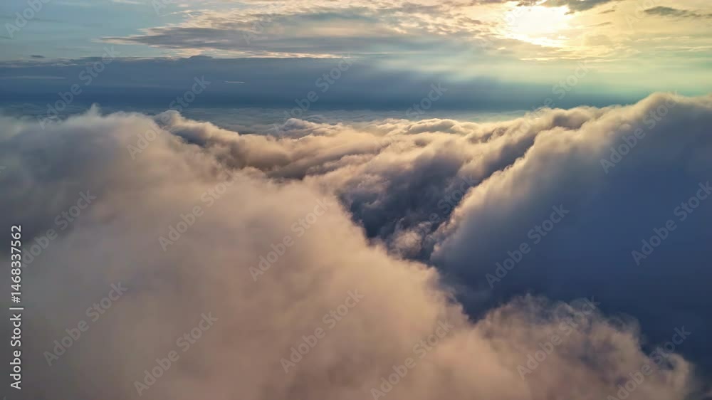 Aerial shot gliding over thick clouds illuminated by soft golden sunlight breaking through the sky Aerial shot gliding over thick clouds illuminated by soft golden sunlight breaking through the sky
