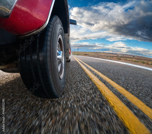 A red pickup truck is driving down a road with yellow lines