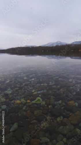 曇った朝の透明な水の湖と山の穏やかな風景。右から左へ。