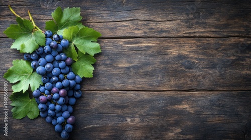 Fresh dark purple grapes and leaves on rustic wood.