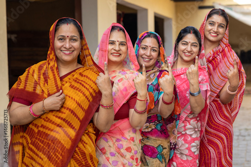фотографія Group of happy rural indian women standing in queue showing their finger marked with black ink after casting vote