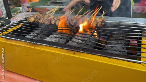 Grilling satay with hot coals on a yellow box stove with wire lines. hot, smoky embers from the satay burner
