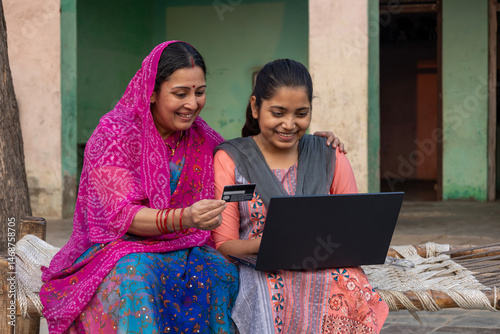 Photography Indian Rural woman using laptop with her daughter while using a debit card at vi
