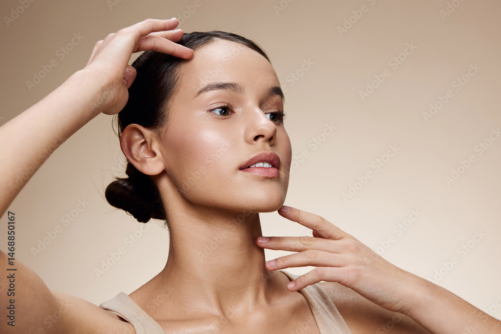 Naklejka premium A young woman with smooth skin, showcasing skincare routine, natural beauty, and self care, wearing a neutral sleeveless top against a soft beige background
