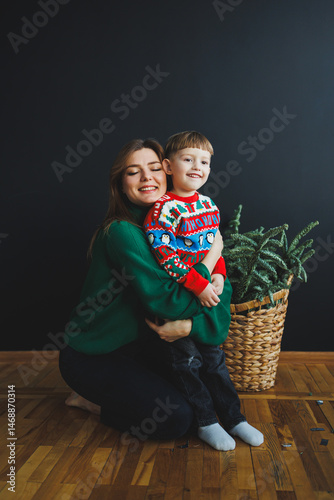 Obraz na płótnie Mother and little son at home on Christmas, child smiles at mother, congratulates and gives unexpected gift. Woman mother receives gift from son on birthday. Family holiday, love concept w salonie