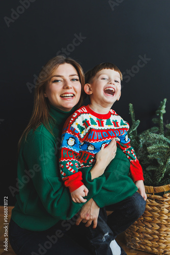 Obraz na płótnie Mother and little son at home on Christmas, child smiles at mother, congratulates and gives unexpected gift. Woman mother receives gift from son on birthday. Family holiday, love concept w salonie