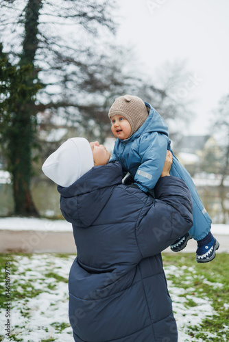 Obraz na płótnie Smiling mother playing with her one-year-old son on the street. Child development and active recreation. Toddler boy playing with his mother on the playground. w salonie