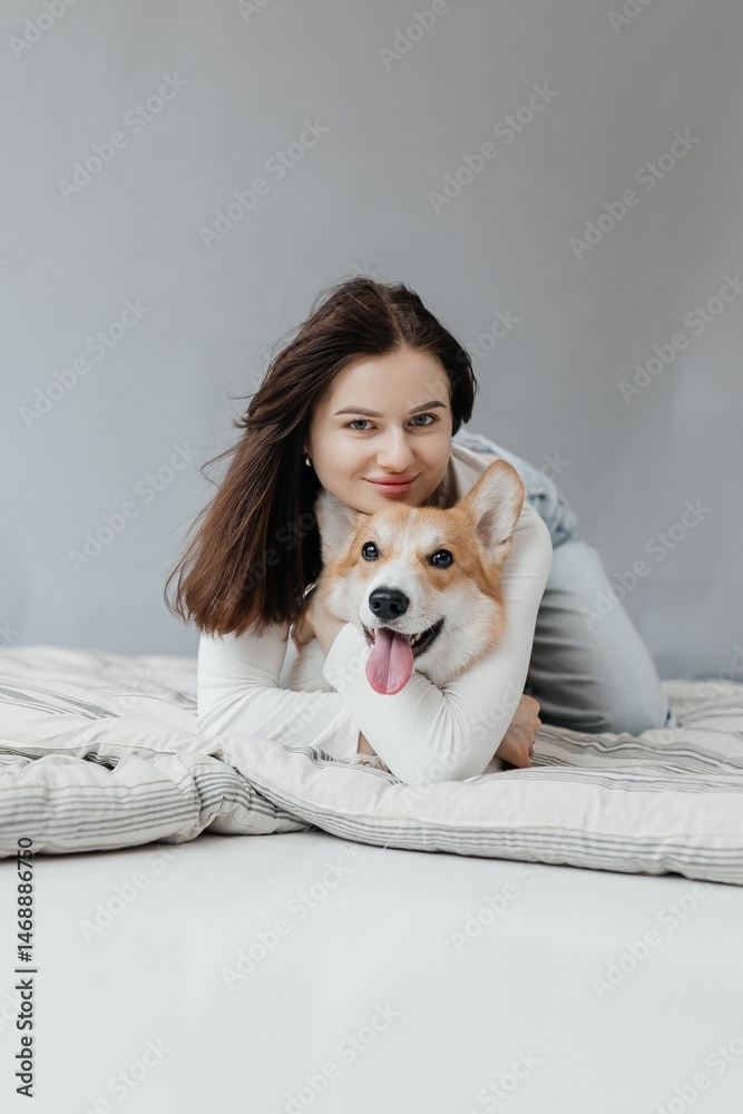 Cute brunette woman in white t-shirt and jeans hugging corgi puppy on white background. Love for animals, pets concept. cheerful woman holding welsh corgi dog.