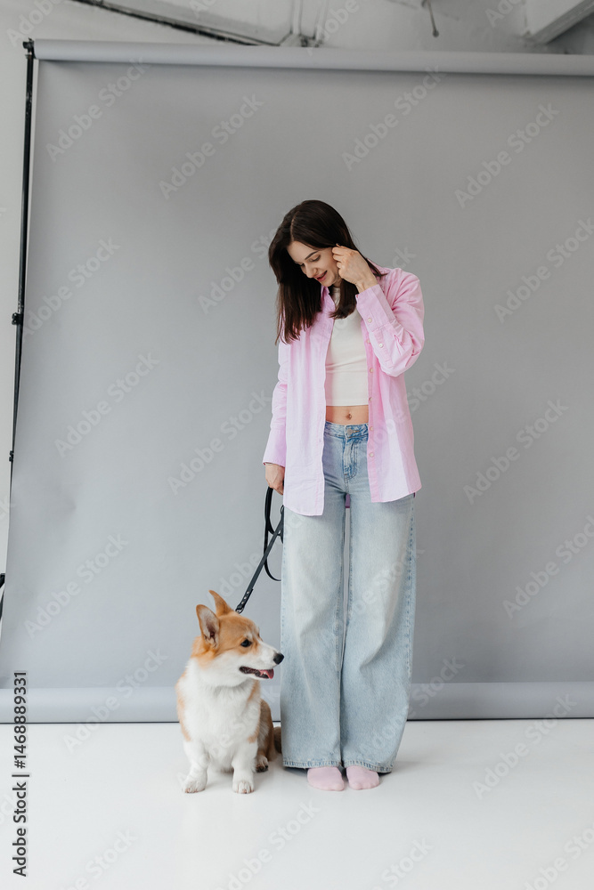 Cute brunette woman in white t-shirt and jeans hugging corgi puppy on white background. Love for animals, pets concept. cheerful woman holding welsh corgi dog.