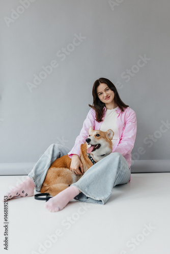 Obraz na płótnie Young woman in jeans and shirt with dog on white background. Dog is man's friend. Pet love concept. w salonie