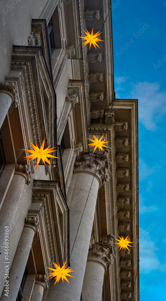 Fototapeta premium Leuchtende Weihnachtssterne an der prachtvollen Fassade eines denkmalgeschützten ehemaligen Bankgebäudes in Berlin-Mitte