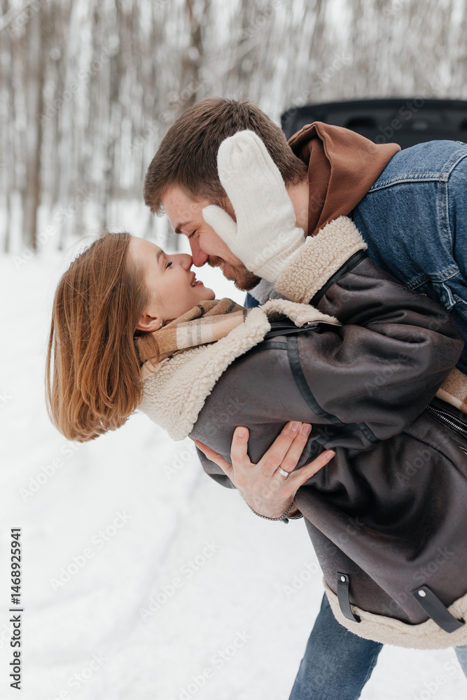 A couple in love on a walk in a snowy winter park. A walk in the winter forest of two happy people. A guy and a girl holding hands and hugging.