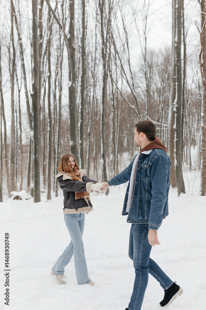 A couple in love on a walk in a snowy winter park. A walk in the winter forest of two happy people. A guy and a girl holding hands and hugging.