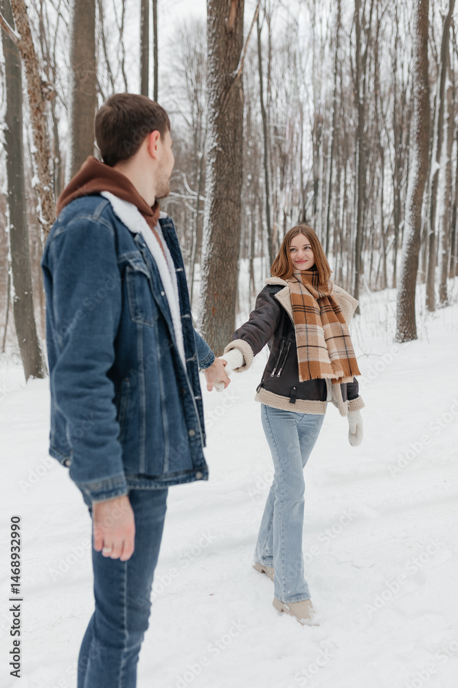 A couple in love on a walk in a snowy winter park. A walk in the winter forest of two happy people. A guy and a girl holding hands and hugging.