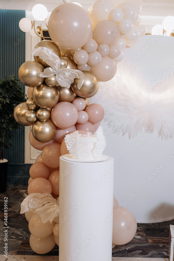 White cake for celebrating a child's baptism. Sweet cake with white wings. Photo zone for a child's baptism.
