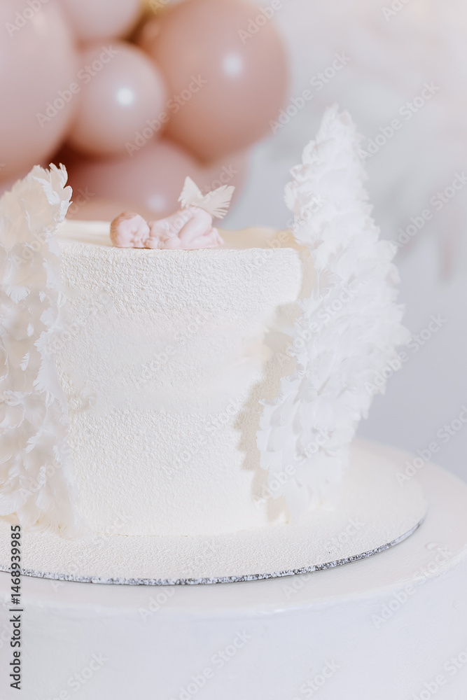 White cake for celebrating a child's baptism. Sweet cake with white wings. Photo zone for a child's baptism.