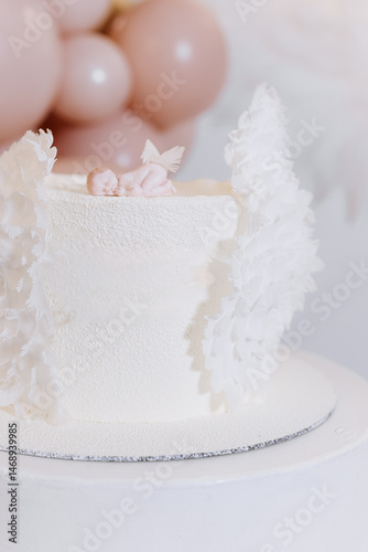 White cake for celebrating a child's baptism. Sweet cake with white wings. Photo zone for a child's baptism.