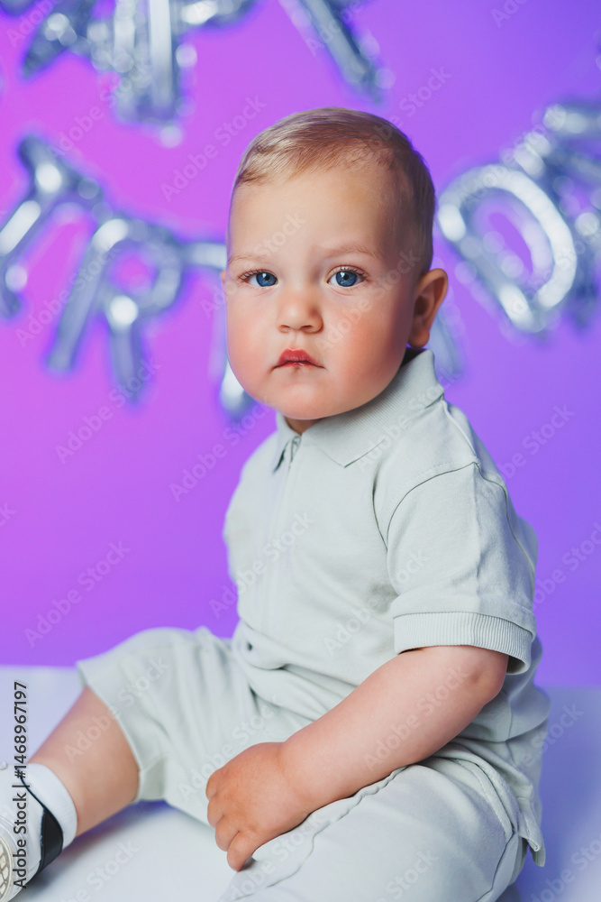 Birthday of a 1 year old boy. A small one year old boy in a t-shirt runs and laughs around the room. A toddler boy is happy and smiling.