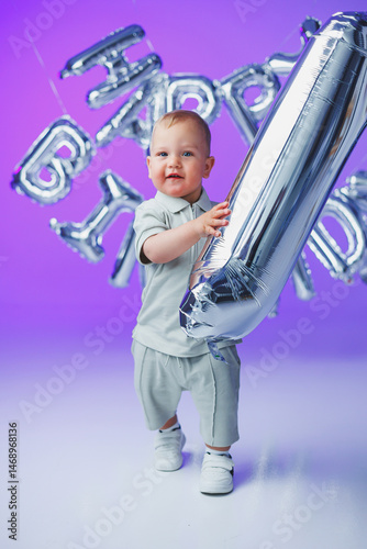 Obraz na płótnie A little one-year-old boy in a t-shirt runs and laughs around the room. A toddler boy is happy and smiling. w salonie