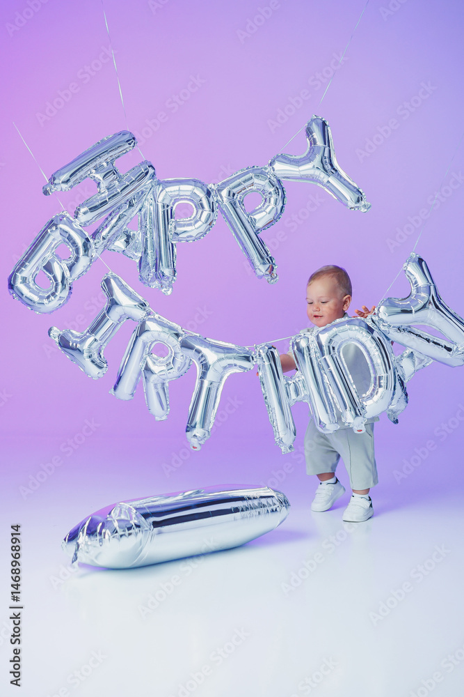 A little one-year-old boy in a t-shirt runs and laughs around the room. A toddler boy is happy and smiling.