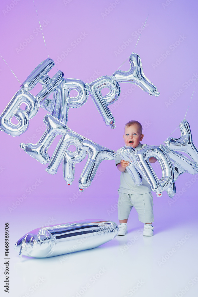A little one-year-old boy in a t-shirt runs and laughs around the room. A toddler boy is happy and smiling.