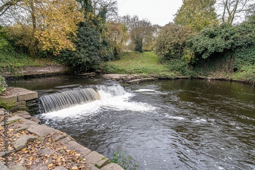 Autumnal river flowing over a small stone weir